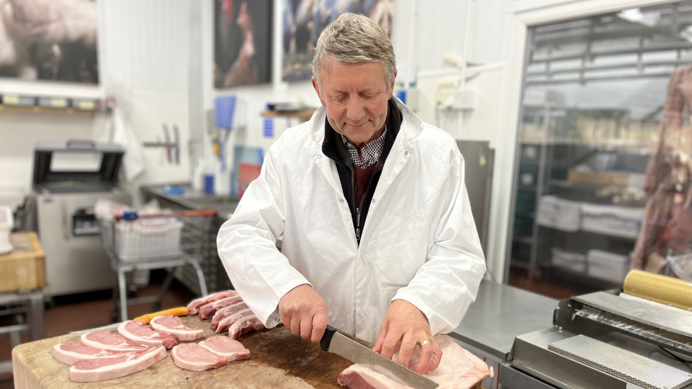 Butcher Jeremy Thickitt cutting up pork chops