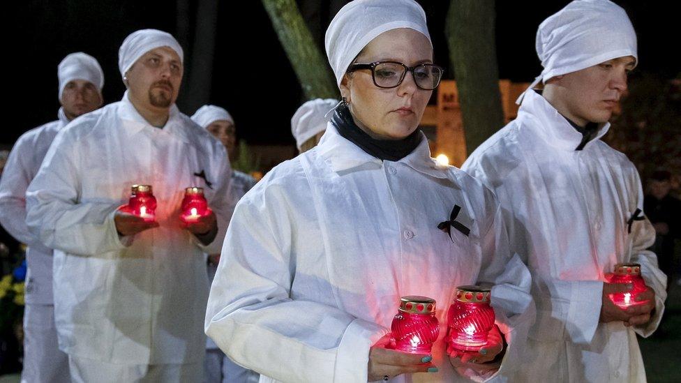 Staff of the Chernobyl nuclear plant hold candles as they visit a memorial, dedicated to firefighters and workers who died after the Chernobyl nuclear disaster, during a night service in the city of Slavutych, Ukraine, April 26, 2016. REUTERS/Gleb Garanich