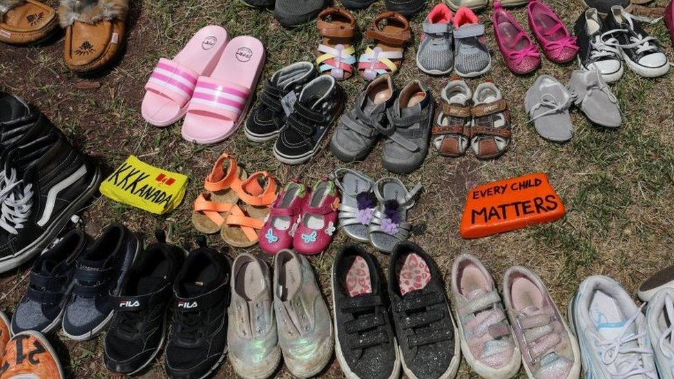 Children's shoes are placed at the base of a statue in Toronto