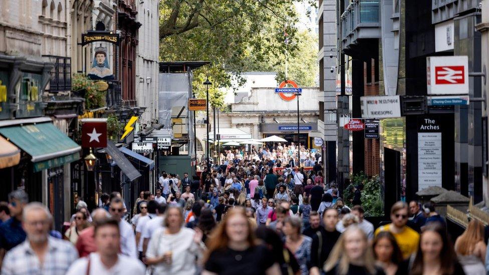 A crowd of people walk through Villiers Street