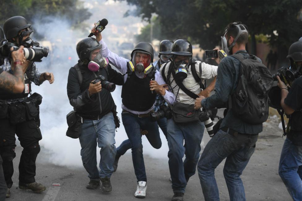 An injured journalist is helped by others during a street protest in Venezuela