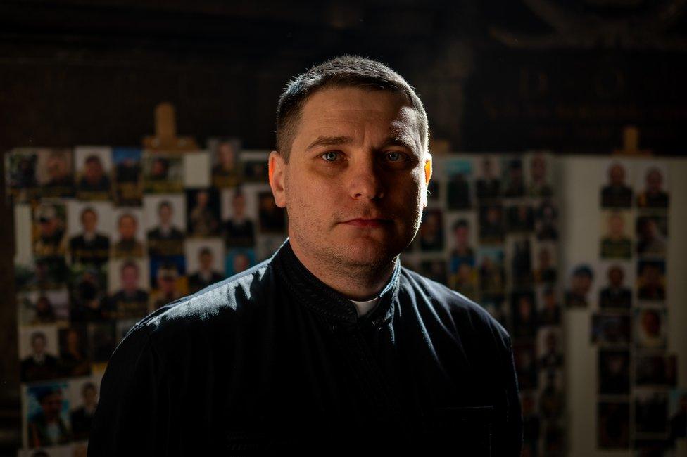 Father Vsevolod stands in front of the portraits of the dead. "We will be honouring the fallen all our lives," he said