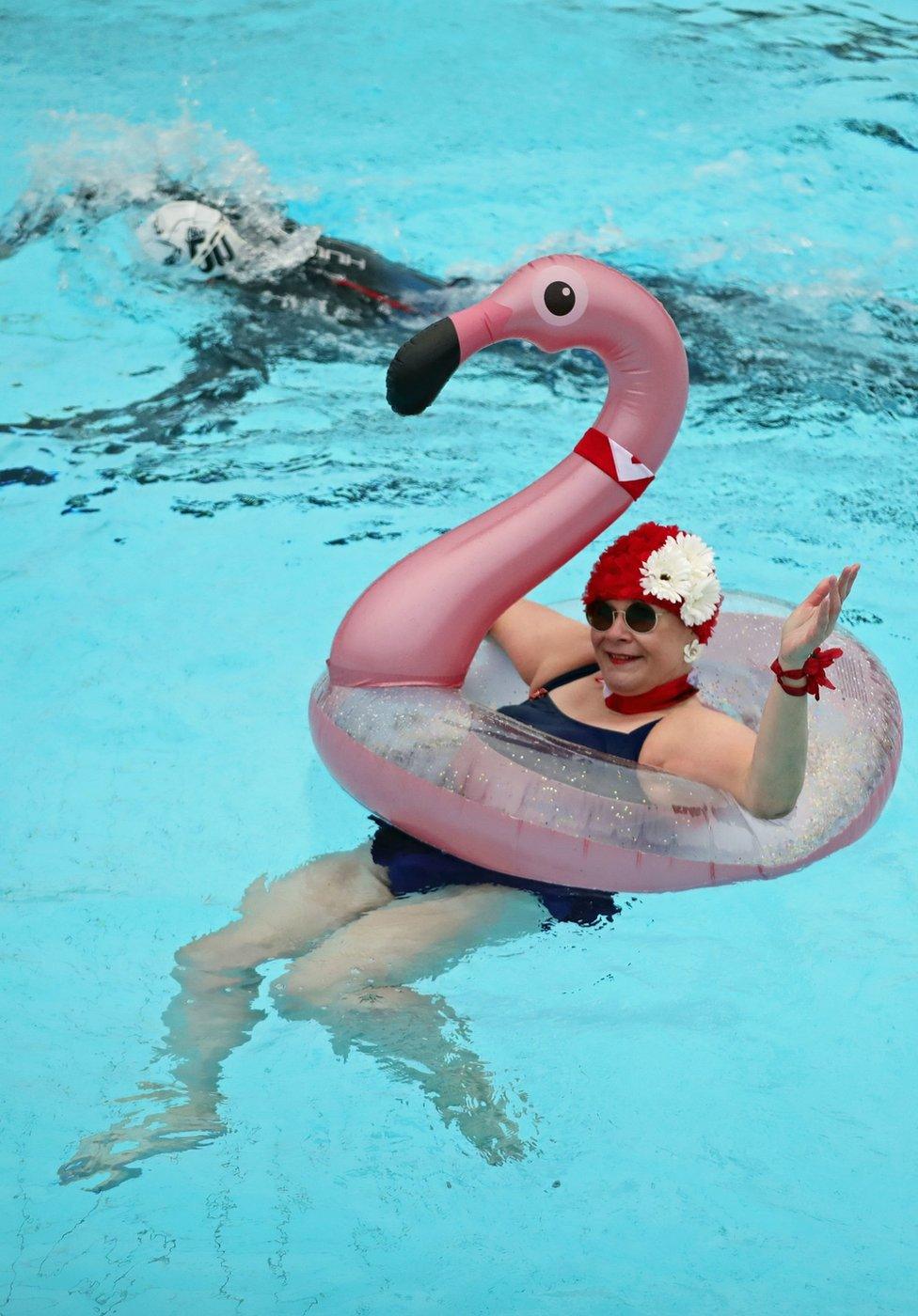 A lady poses in a lido pool with an inflatable flamingo