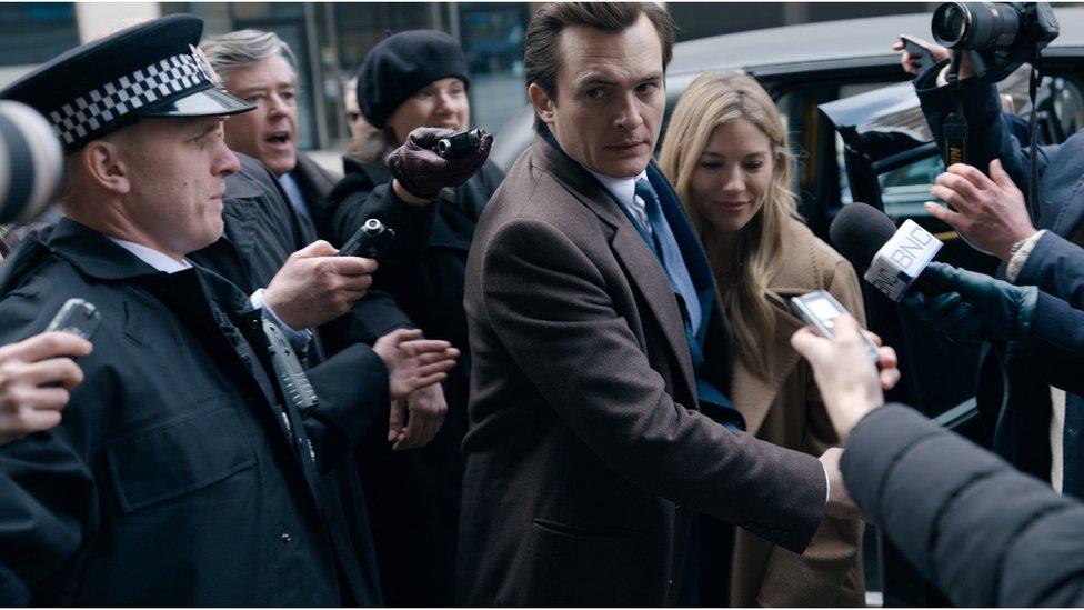 Policeman and press photographers surrounding a man and woman