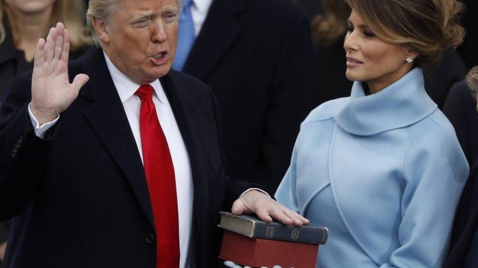 Donald Trump takes the oath of office as his wife Melania holds a bible