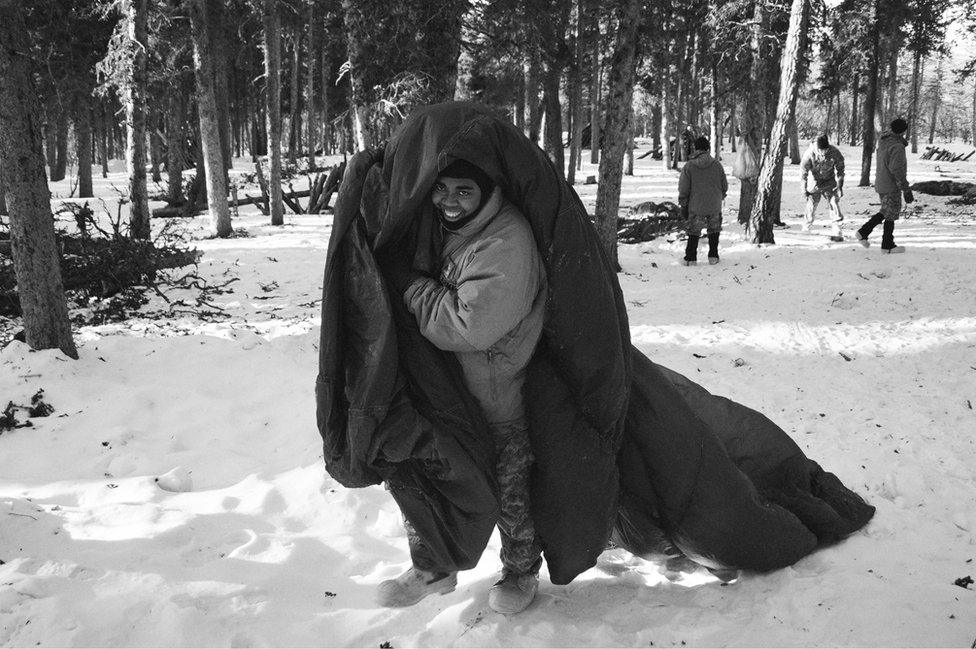 A soldier walks with a parachute to the thermal shelter he is building