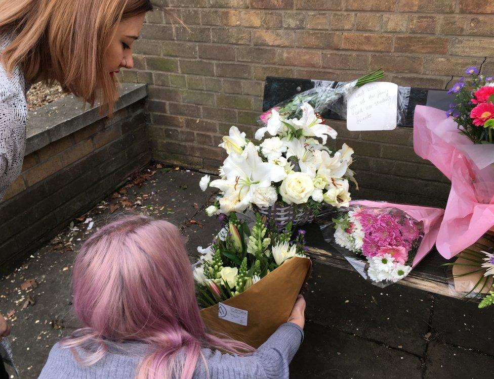 Two women placing flowers on a bench