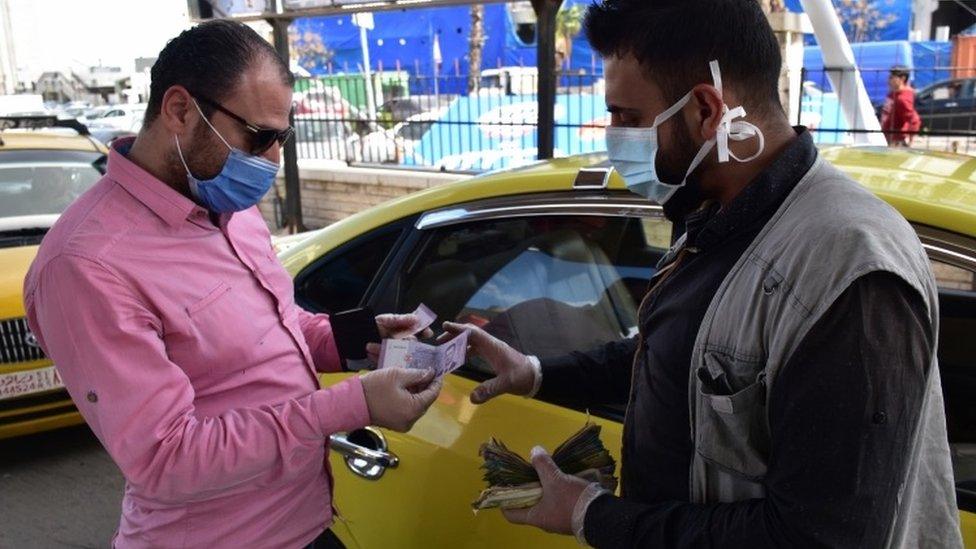 A man pays for petrol at a petrol station in Damascus, Syria (28 March 2020)