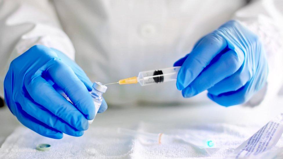 Doctor filling syringe with vaccine