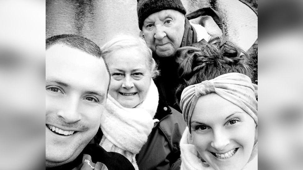 Charlotte posing for a photograph with her Mum, Dad and brother, Tim by a river