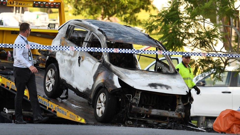 The burnt-out family car is removed from the scene