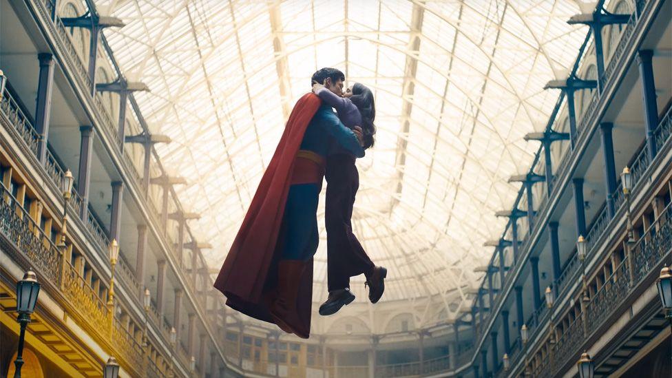 Superman and Lois Lane kissing while in mid-air in the middle of an ornate old building in a still from the trailer