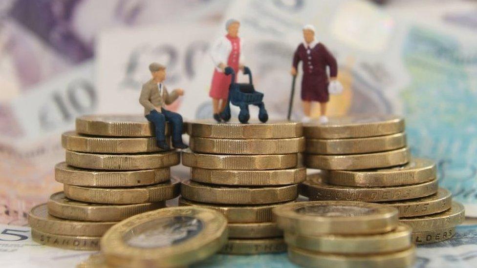 Models of elderly people on a pile of coins and bank notes