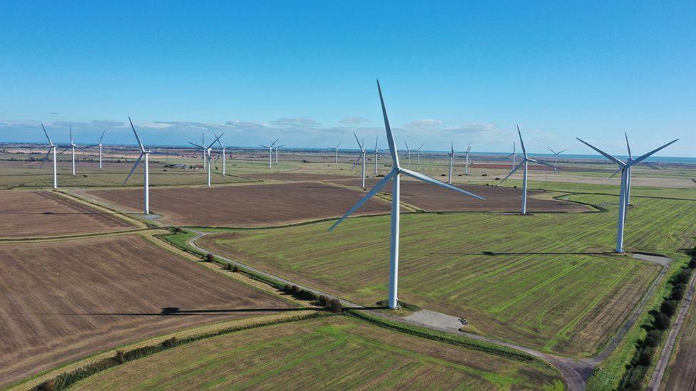 An aerial view of a number of onshore wind turbines located on green fields