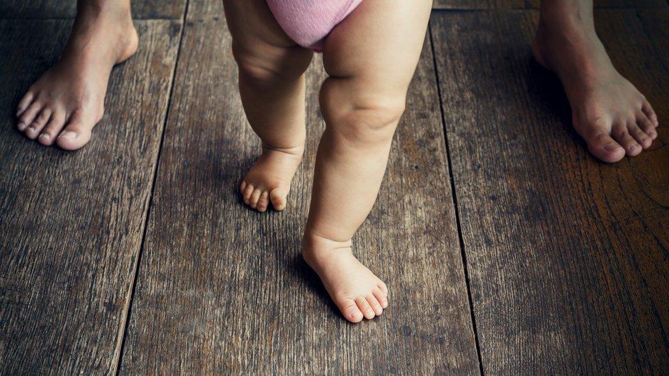 Happy baby learning to walk with mother help - Stock image