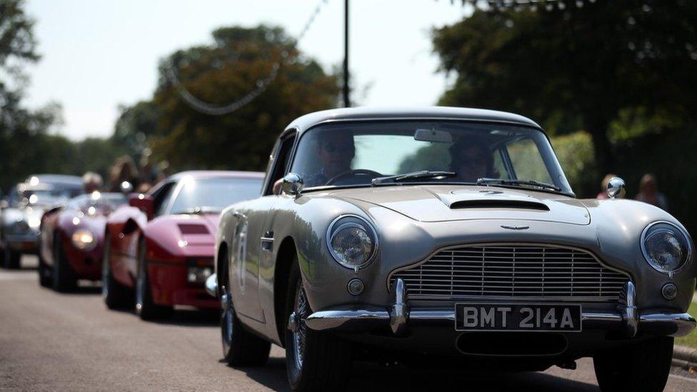 The James Bond Aston Martin DB5 leads a convoy of classic and exotic cars