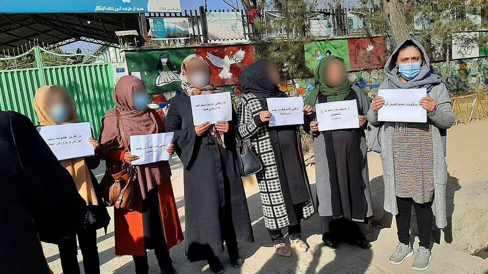 Women hold up signs during a protest on the street