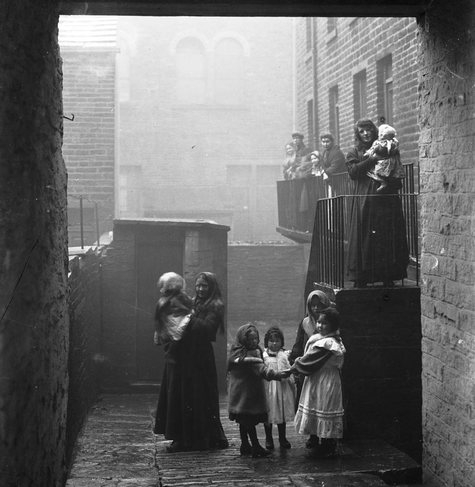 Woman and children down a back alley. c1905-8