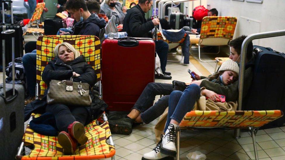 Passengers rest on camp beds in a temporary shelter inside a building of the railway station after arriving on a train from Kyiv in Ukraine to Przemysl, Poland