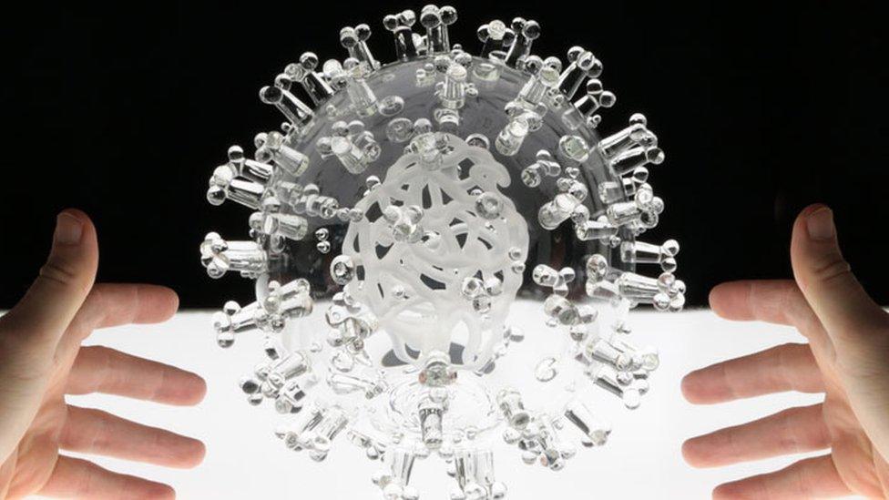 A clear glass sculpture of the Covid-19 virus