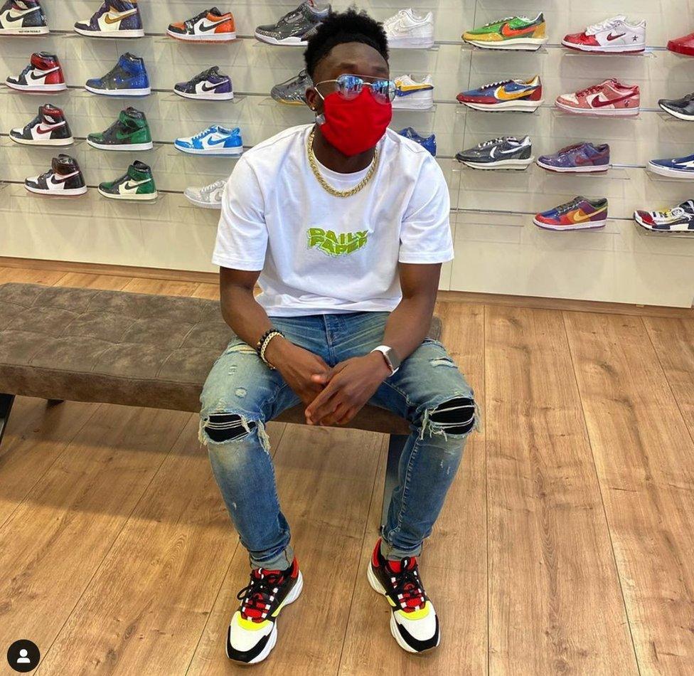 Alphonso Davies sitting in a trainer store