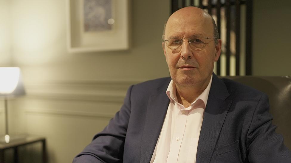 Porf Charles McLachlan, sitting in an office illuminated by lamplight