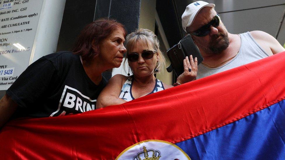 Supporters of Serbian tennis player Novak Djokovic listen to the court hearing at the offices of his legal team that will decide whether or not he can stay in Australia and defend his Open title, in Melbourne, Australia, January 16, 2022.