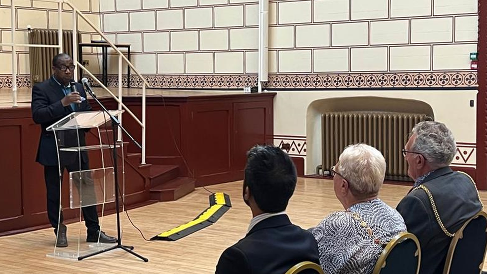 A speaker at a podium in front of an audience