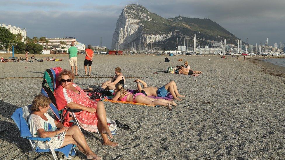 Beachgoers lie in the sand as the British territory of Gibraltar looms behind in La Linea de la Concepcion, Spain (22 June 2016)