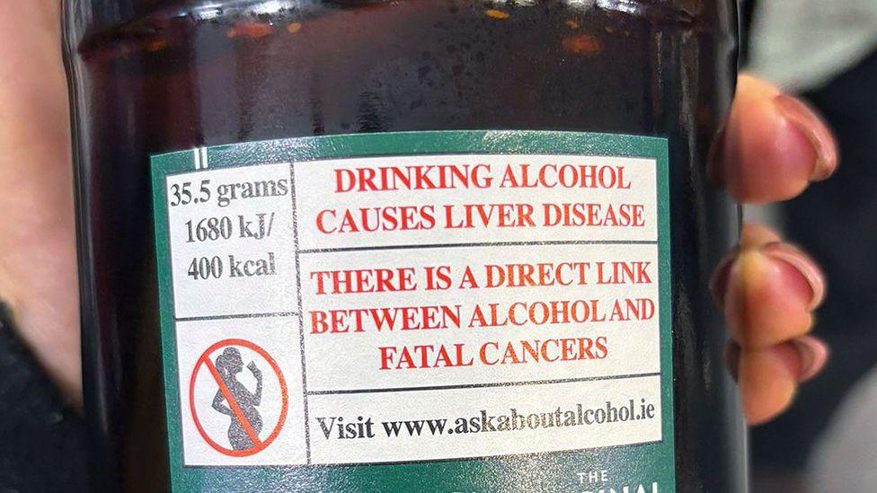 Alcohol causes liver disease and cancers warning label on the back of a bottle of cider