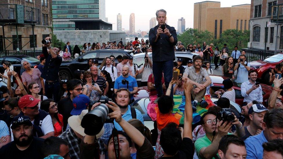 People gather at Tudor City on 42nd St in Manhattan to watch and photograph the phenomenon known as Manhattanhenge