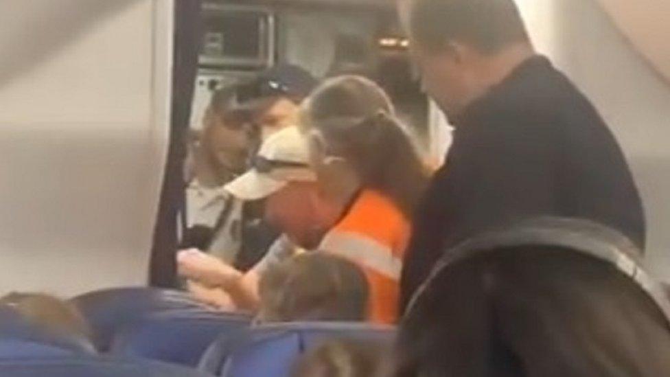 A mechanic attempts to open a toilet door aboard a United Airlines flight