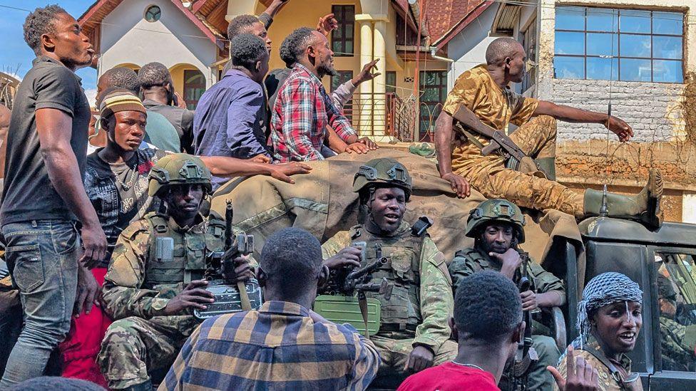 Civilian men cheer and walk alongside a vehicle carrying M23 troops into Bukavu, eastern DR Congo, on Sunday 16 February 2025.