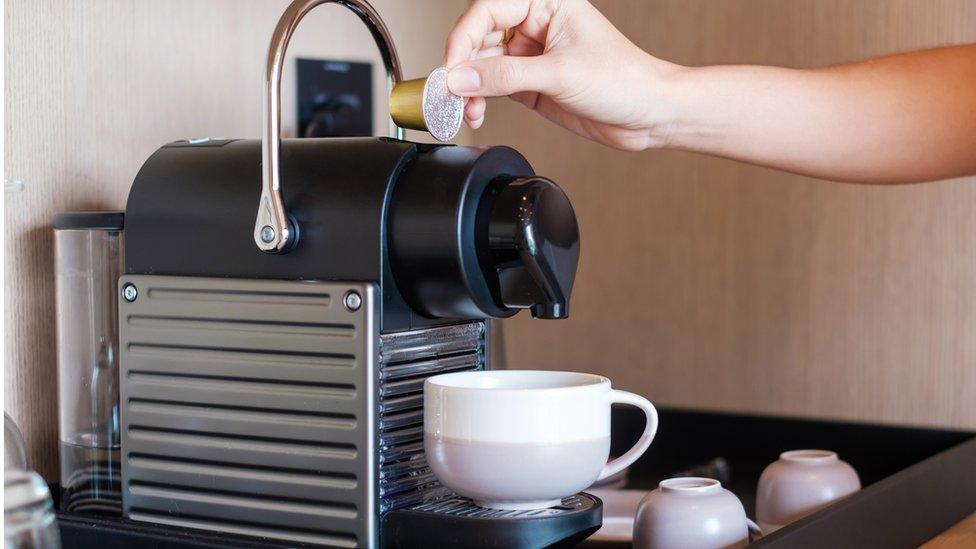 A person making a cup of coffee using a coffee capsule