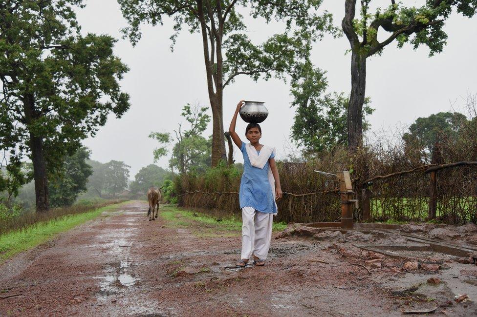 A girl carrying water back to her home.