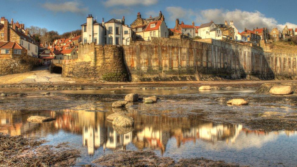 Houses and buildings of Robin Hood's Bay reflected in rockpools