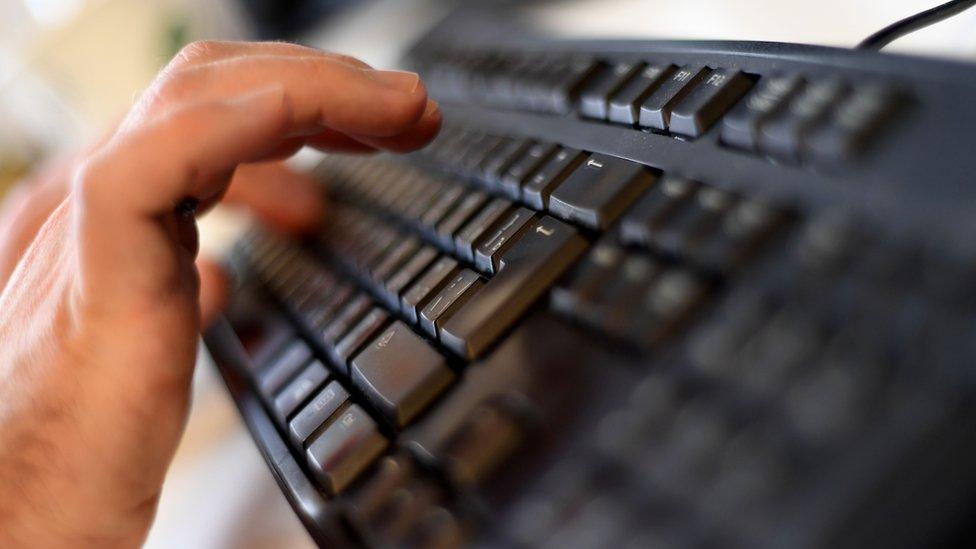 A man typing on a computer keyboard