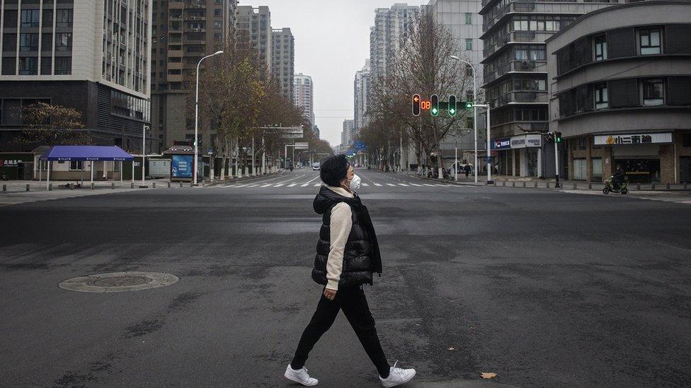 A woman walks on an empty street in Wuhan, China