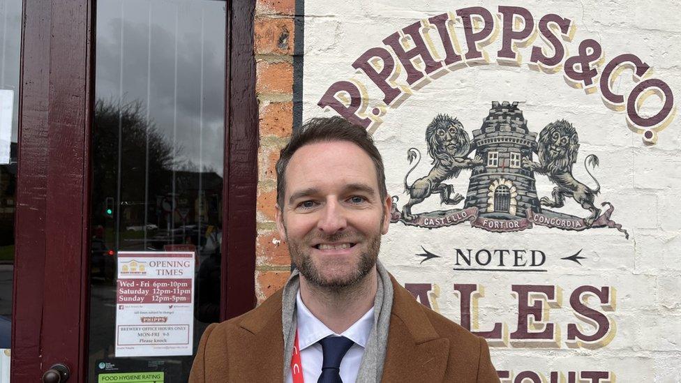 Greg Pickup standing in front of a Phipps sign.