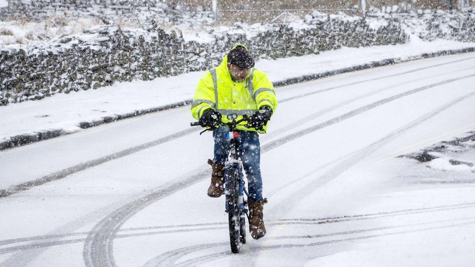 A man rides a bike in snowy conditions in Hawes in the Yorkshire Dales National Park