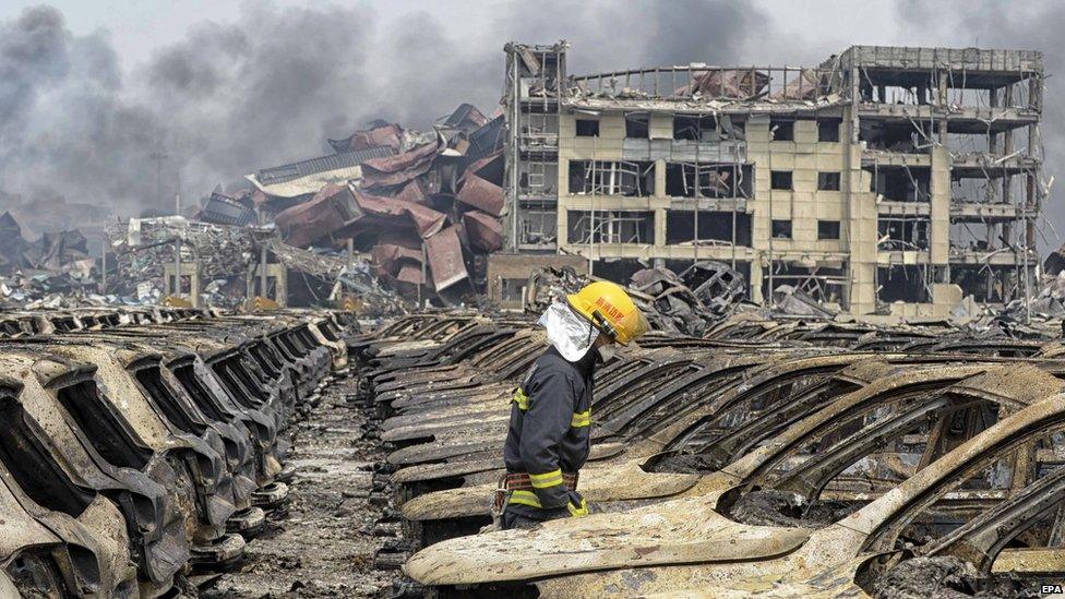 A firefighter walks among damaged vehicles at the site of Wednesday night's explosions in Tianjin, China, on 14 August, 2015