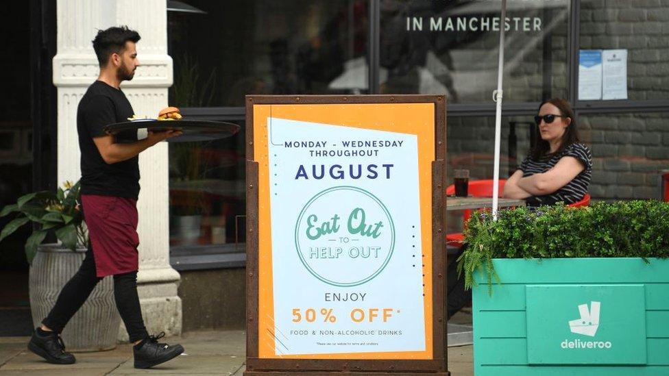 Waiter walks past Eat Out to Help Out sign