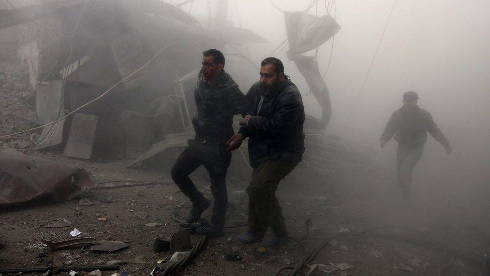 A wounded man is helped from the scene of a reported government air strikes on the town of Arbin, in the besieged rebel-held Eastern Ghouta (8 February 2018)