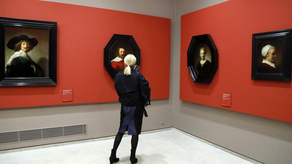 A woman looks at paintings by Dutch painter Rembrandt at the Louvre Museum on 17 February 2017