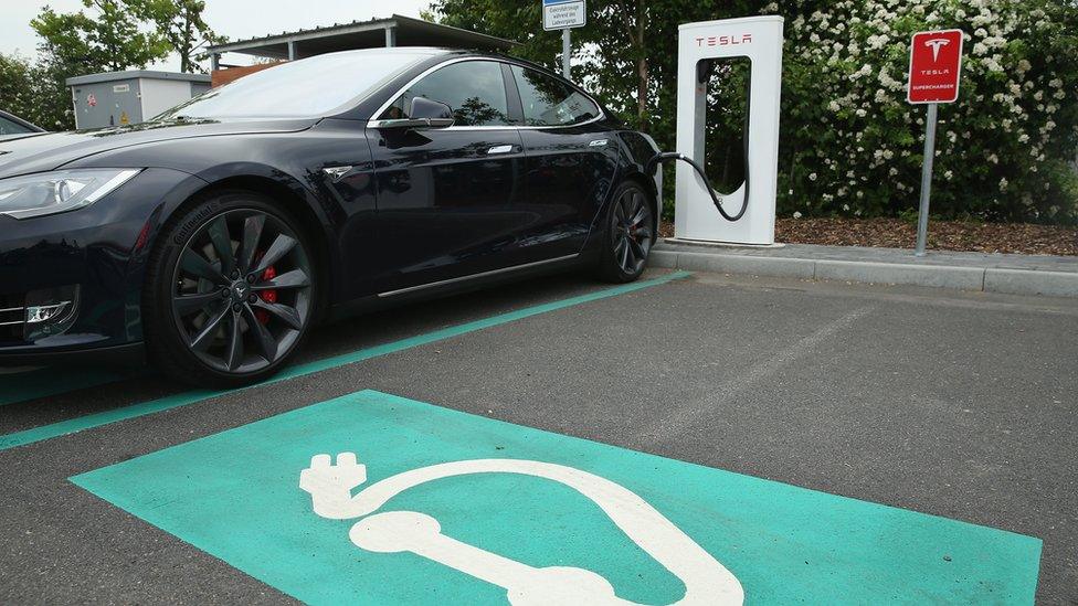 A Tesla electric vehicle plugged in at a charging station in Germany