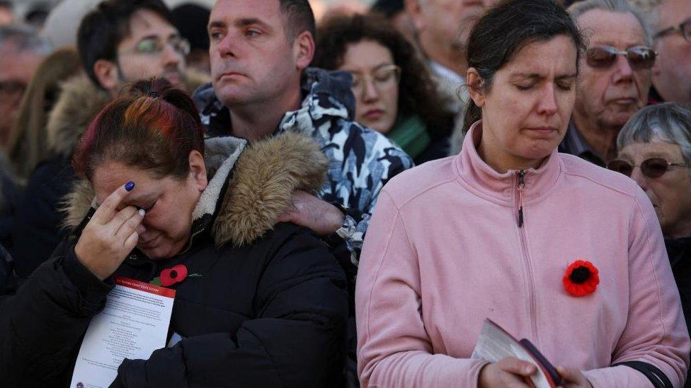 People with poppy pins observe a two-minute silence related to the Remembrance Day, in London