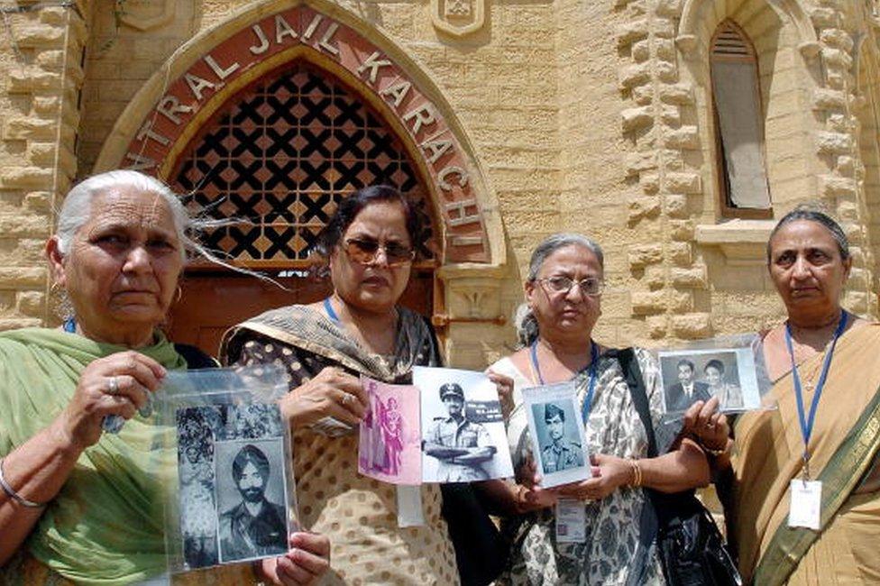 Members of an Indian delegation show pictures of missing Prisoner of War (POW) relatives during a tour of the central jail of Karachi, 04 June 2007