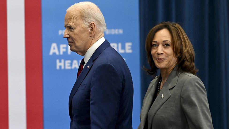 Joe Biden and Kamala Harris walk in front of campaign promotion materials in North Carolina in March