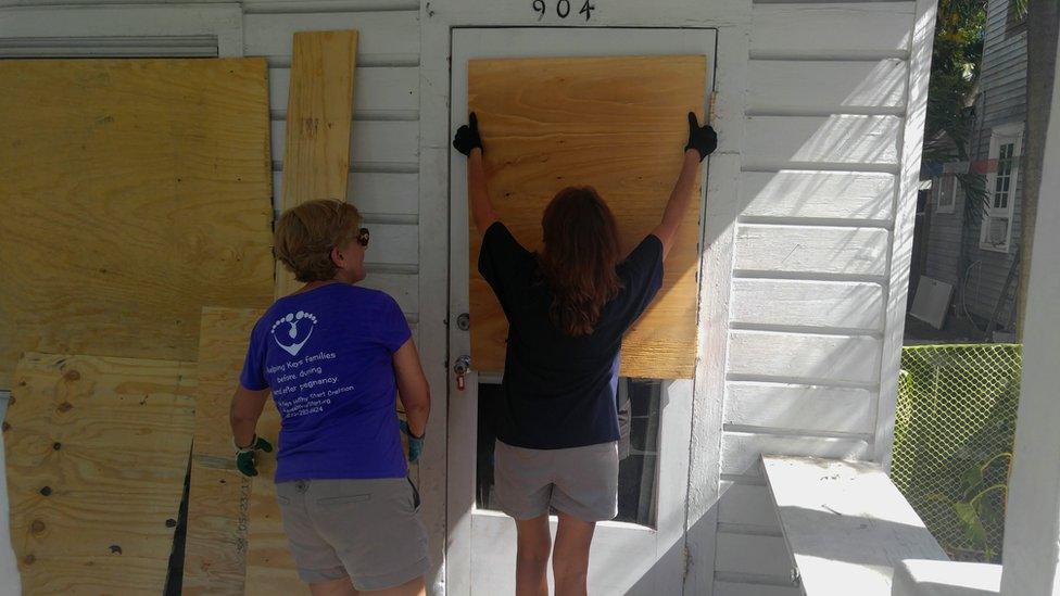 Women putting boards on front door in Key West, Florida