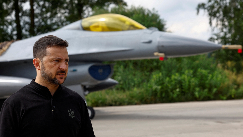 Ukraine President Volodymyr Zelensky speaks to the media in a front of an F-16 fighting aircraft